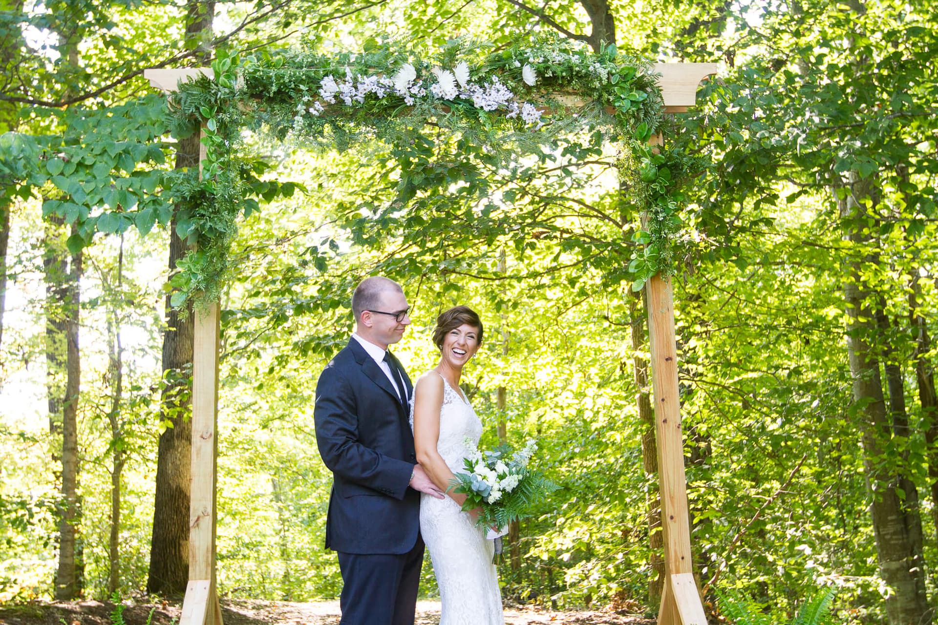 Bride and groom standing in classic prom pose, bride laughing.